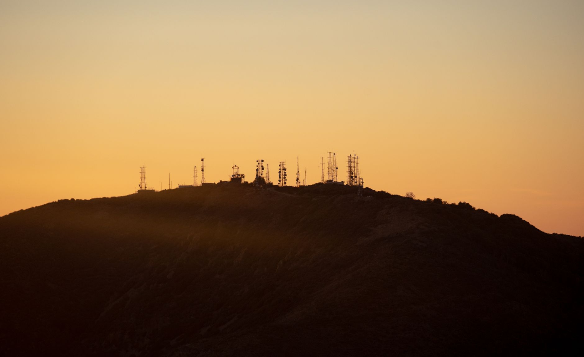 Local SEO in Orange, CA near Chapman University vicinity | OCWebPros. Communication towers silhouetted against an orange suns